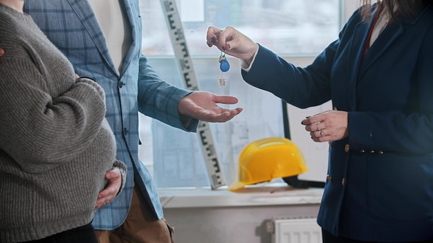 A real estate agent gives the keys to apartment to a young married couple