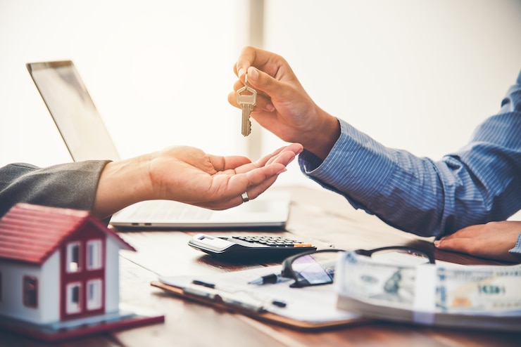 Photo real estate agent gives the keys to the house buyer and signs the contract in the office.