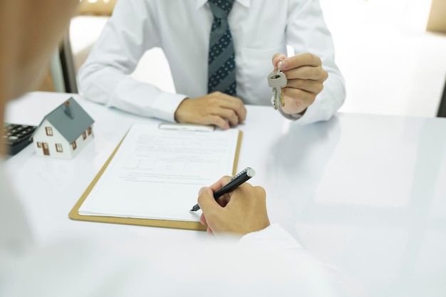 Photo real estate agent giving house keys to client after signing home loan contract