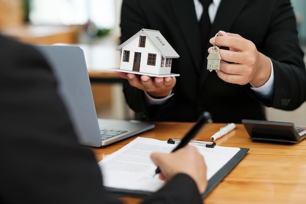 Photo real estate agent giving house keys to client after signing home loan contract