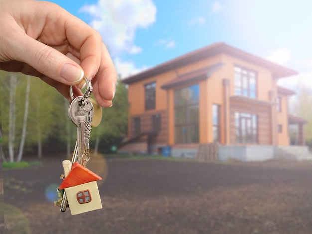 Real estate agent handing a house key Key with a key chain in the shape of house on new home background Mortgage concept