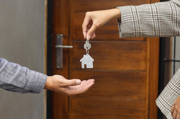 Агент по недвижимости передает ключи от дома перед новым домом.