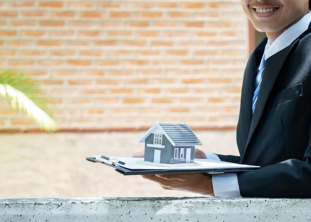 Фото Агент по недвижимости держит домашнюю модель и объясняет бизнес-контракт, аренду, покупку ипотечного кредита или страховки