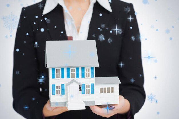 Real estate agent holding a model house against snow falling