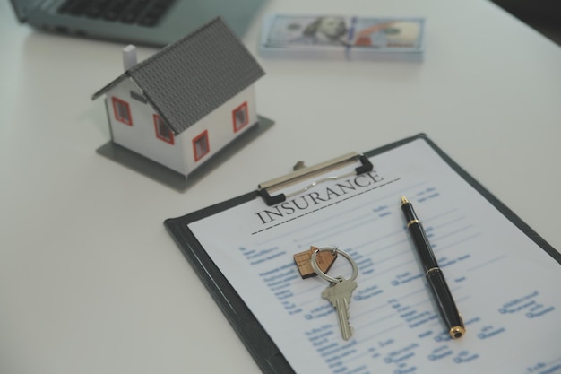 Real estate agent home sales broker is using a pen pointing to the house model and explains the business contract rent buy mortgage loan or home insurance