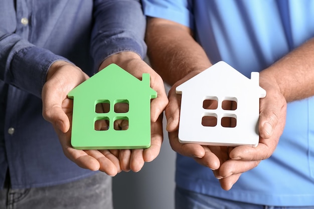 Photo real estate agent and senior man holding house models closeup