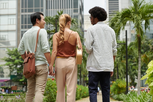 Real estate agent showing new district to young couple view from the back