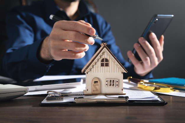 Real estate agent using a pen pointing to the house model.