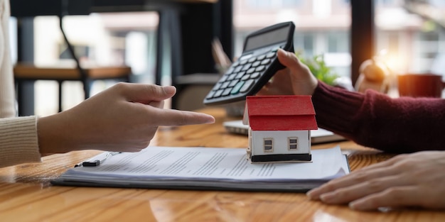 Foto agente immobiliare con calcolatrice che presenta al cliente un tasso di interesse per il prestito immobiliare