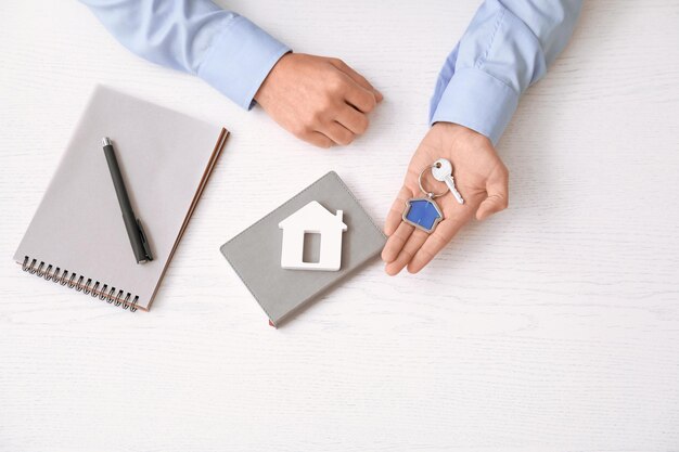 Real estate agent with key and house model at table