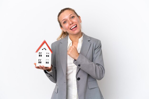 Real estate agent woman holding a toy house isolated on white background celebrating a victory