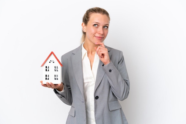 Real estate agent woman holding a toy house isolated on white background and looking up