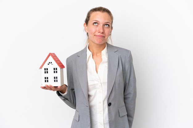 Real estate agent woman holding a toy house isolated on white background and looking up