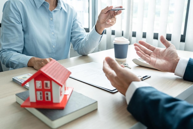 Photo real estate broker agent consulting the customer to a decision making sign insurance form contract home model mortgage loan offer for and house insurance