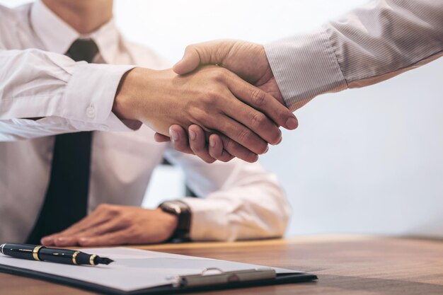 Real estate broker agent and customer shaking hands after signing contract documents for realty purchase Bank employees congratulate Concept mortgage loan approval