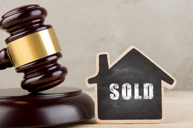 Real estate concept auction gavel and little house with inscription Sold