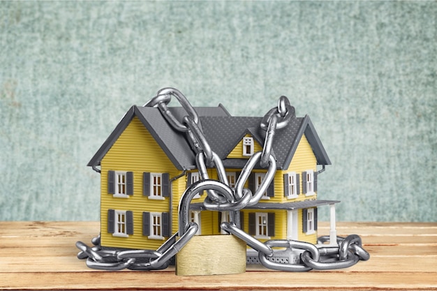 Real estate concept - chain with lock around the home architectural model