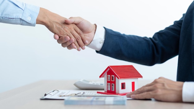 不動産のコンセプトは、土地売買契約を結ぶことを受け入れるために握手する家の不動産と彼のクライアントです。