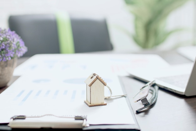 Real estate concept, house model on finance paper with home key on table