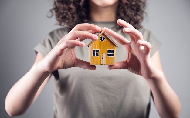 Real estate concept, woman holding house model.