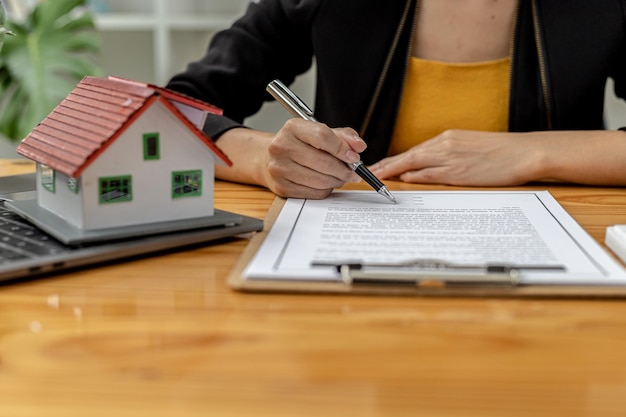 Real estate contract agreement concept. Buyer is signing house purchase contract with seller. Salesperson calculates house purchase cost and explains details on contract.