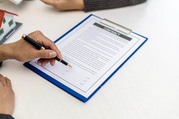 Real estate contract agreement concept. Buyer is signing house purchase contract with seller. Salesperson calculates house purchase cost and explains details on contract.