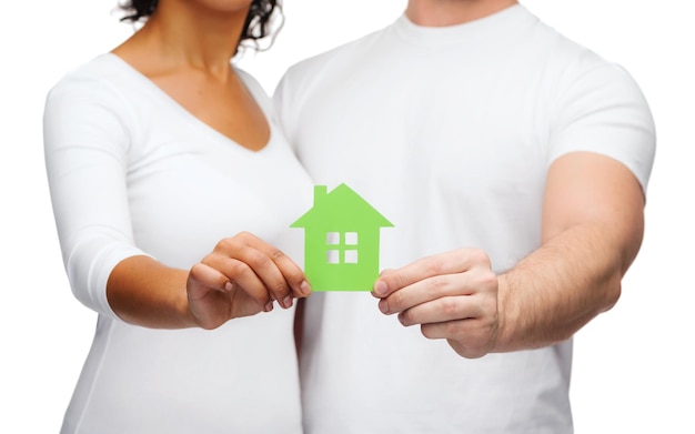 不動産、家族、エコのコンセプト-緑の家を持っているカップルの手のクローズアップ写真