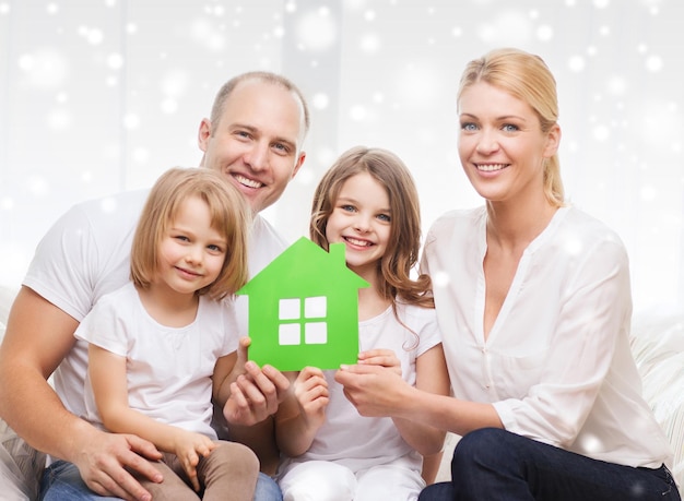 不動産、家族、人々、家のコンセプト-緑の紙の家を持っている2人の少女と笑顔の両親