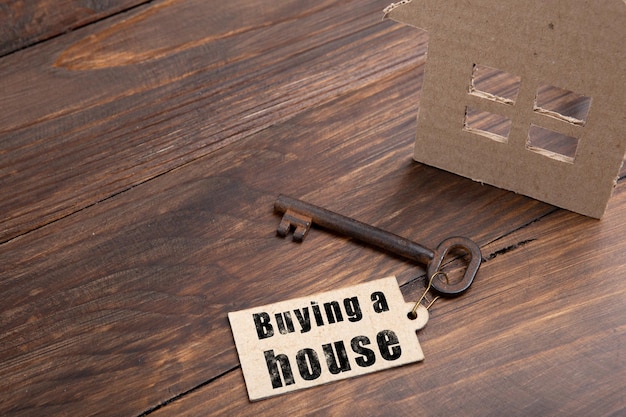 Photo real estate insurance concept old key with tag and cardboard house on wooden background