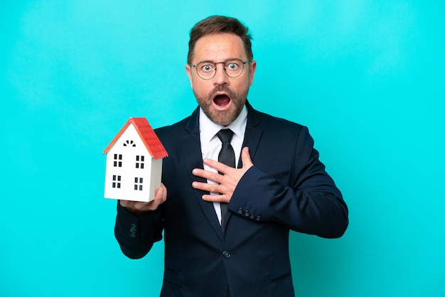 Real estate middle age agent man isolated on blue background surprised and shocked while looking right