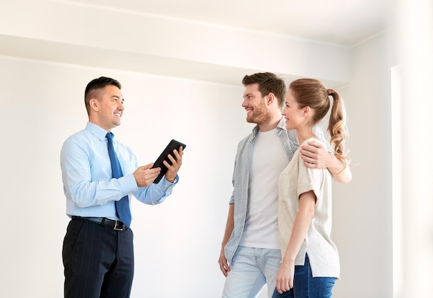 Foto tecnologia ipotecaria immobiliare e concetto di persone coppia felice e agente immobiliare con tablet pc computer nella nuova casa