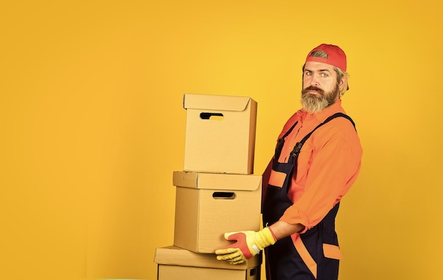 Photo real estate moving day renovation preparation bearded hipster indoors unpacking moving boxes bearded man courier hold boxes moving to new apartment post service bearded loader in uniform