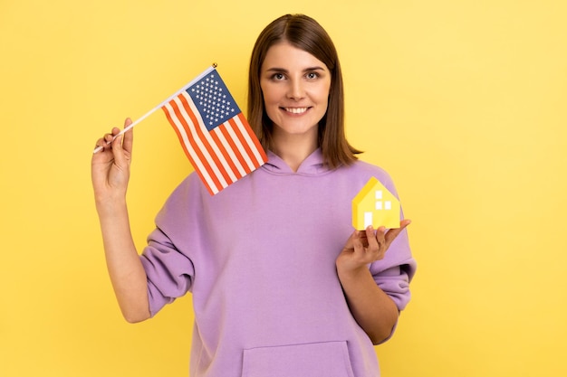 Real estate purchase in America immigration Woman holding american flag and paper house