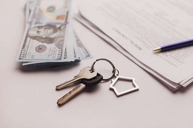 Договор купли-продажи недвижимости с деньгами и ключами от дома на белом столе
