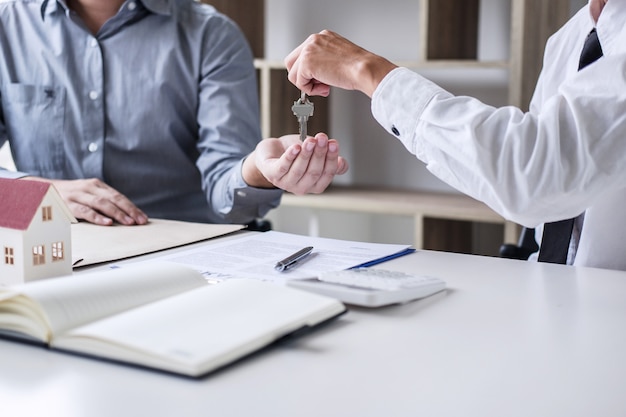 Real estate Sales manager giving keys to customer after signing rental lease contract 