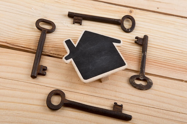 不動産のセキュリティ販売または賃貸コンセプトの小さな家のモデルと木製の背景の古い鍵