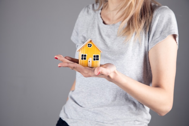 Foto immobiliare, donna che tiene il modello di casa in legno