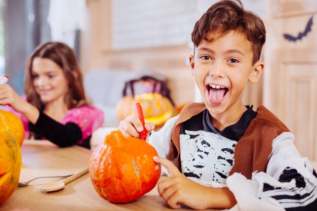 本当の興奮。興奮しながら舌を見せてハロウィーンの衣装を着てかわいい晴れやかな少年