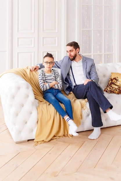 Real family father and son  sitting on sofa at home