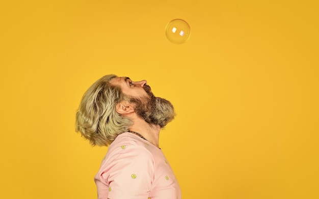 Real happiness mature man blowing soap bubbles stay carefree at any age man with bubble blower happy hipster in playful mood Fall into childhood feeling childish and childlike copy space