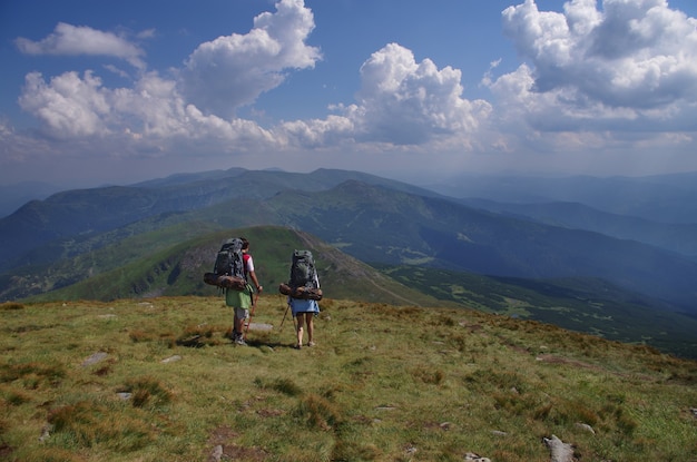 Настоящие туристы с рюкзаком на тропе Панорама гор весной или летом камни и трава