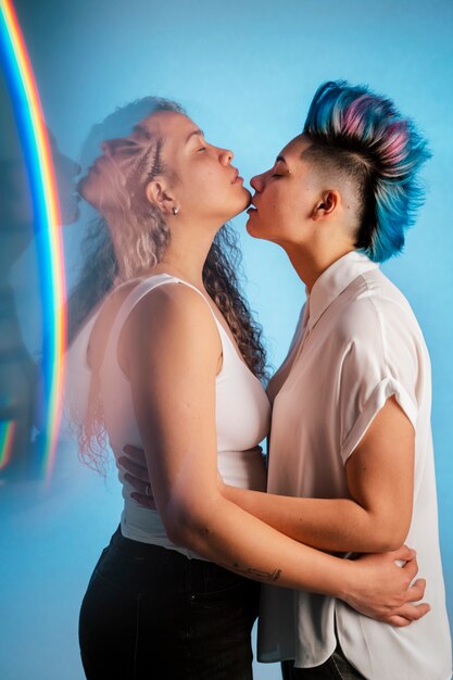 Foto coppia lesbica reale che abbraccia e bacia con l'iconico simbolo lgbt arcobaleno.