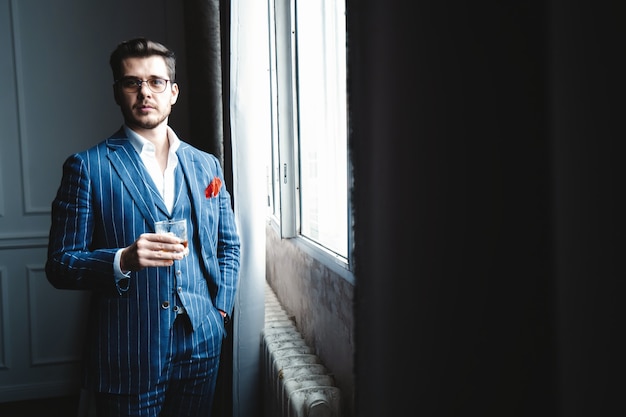 Real macho. Handsome young man in suit looking at camera and smiling while standing indoors.