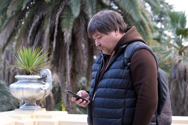 Real middle aged overweight man looking at phone screen smartphone in the hands of a man