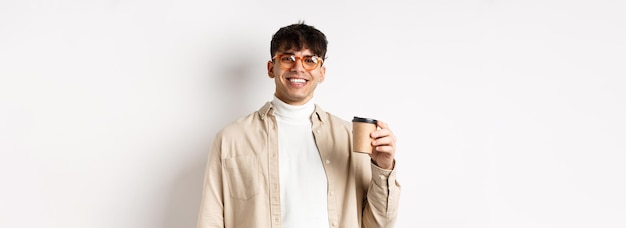 Настоящие люди, счастливый молодой человек, пьющий кофе из бумажного стаканчика, заказывают еду на вынос в любимом кафе, улыбаясь