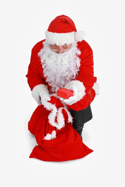 Real santa claus carrying big bag full of gifts isolated on white background