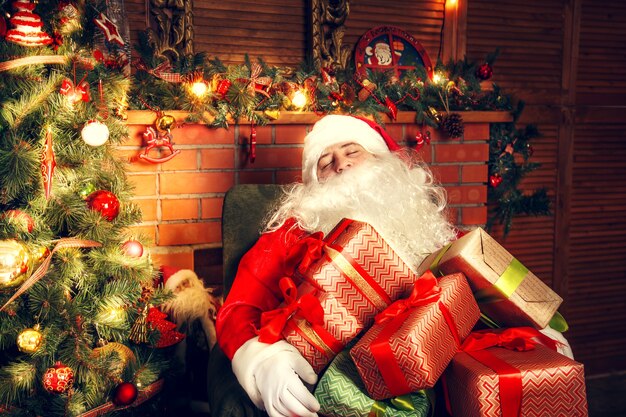本物のサンタクロース。クリスマスツリーの近くのリビングルームで眠っているサンタクロース。