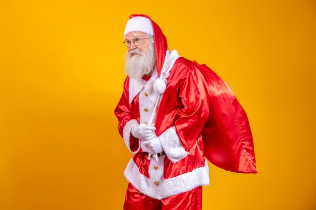 Real Santa Claus with a red background, wearing glasses, gloves and a hat looking side.