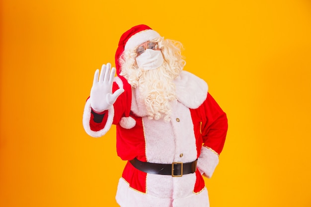 Настоящий Санта-Клаус на желтом фоне, в защитной маске от covid19. Рождество с социальной дистанцией. COVID-19