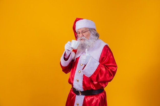 Real Santa having a coffee on yellow background with free space for text.